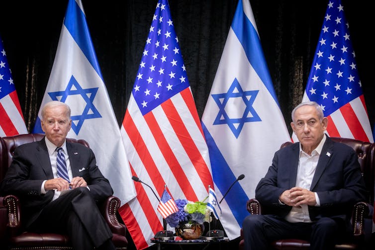 US US president, Joe Biden, sots with Israeli prime minister Benjamin Netanyahu with their national flags in the background.
