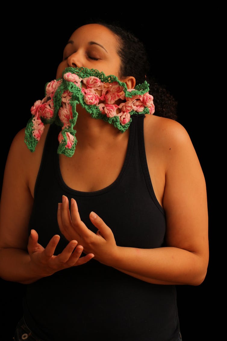 A figure seen with crocheted flowers appearing to emerge from the mouth.