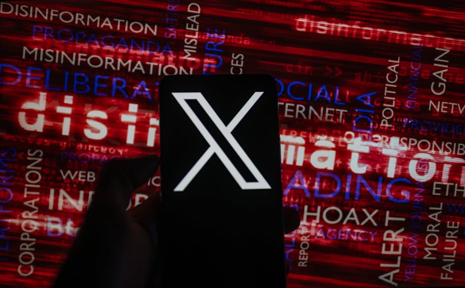 X social media icon logo displayed on a smartphone with words like disinformation seen on screen in the background.
