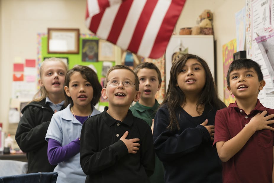 Six students stand for the Pledge of Allegiance with their hands placed on their hearts.