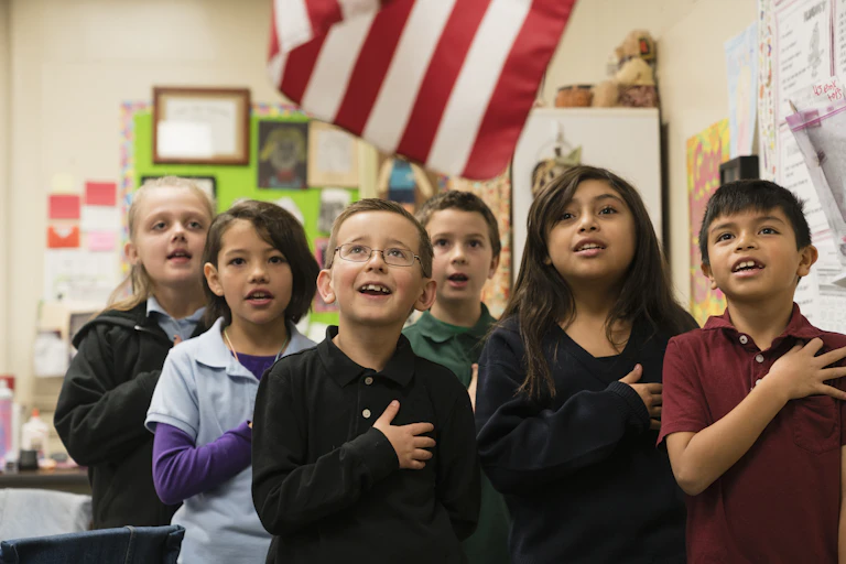 Six students stand for the Pledge of Allegiance with their hands placed on their hearts.