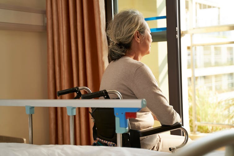 Woman sits it wheelchair in hospital