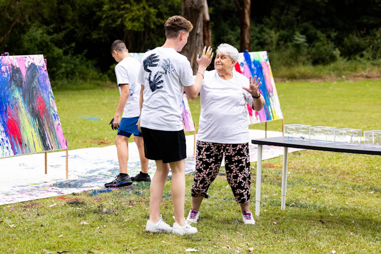 Tom and Lorraine placing painted handprints on each other during filming