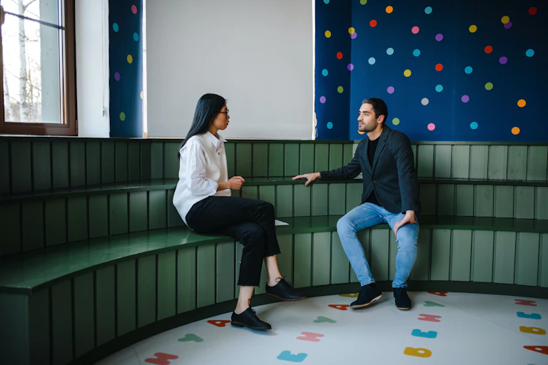A woman and a man on a bench in a classroom.