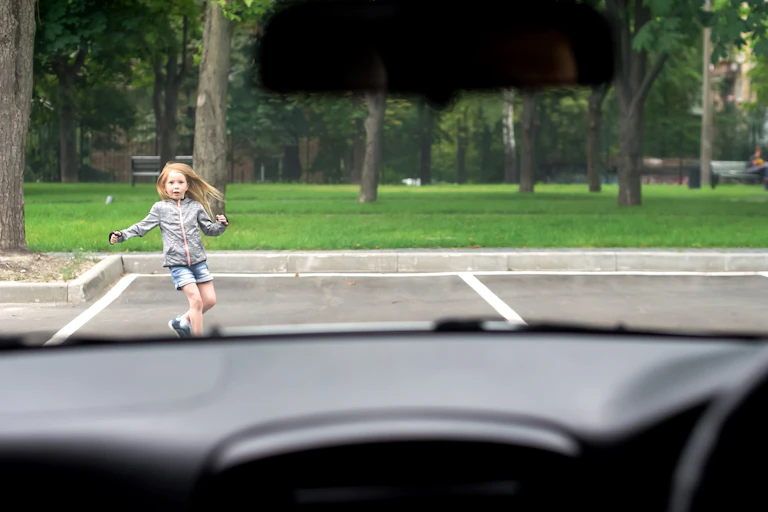 Young girl seen through windscreen running in front of car