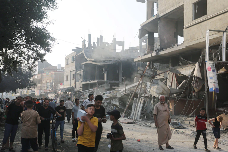 Palestnian people walk amid the rubble of homes destroyed by Israeli airstrikes October 2023.
