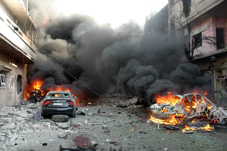 Buildings on either side of a street burn following an airstrikes on Homs in Syria, April 2014.