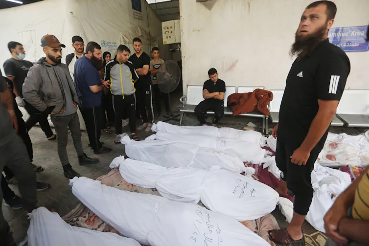 People inspect the shrouded bodies of Palestinians killed in Israeli airstrikes, October 25 2023.
