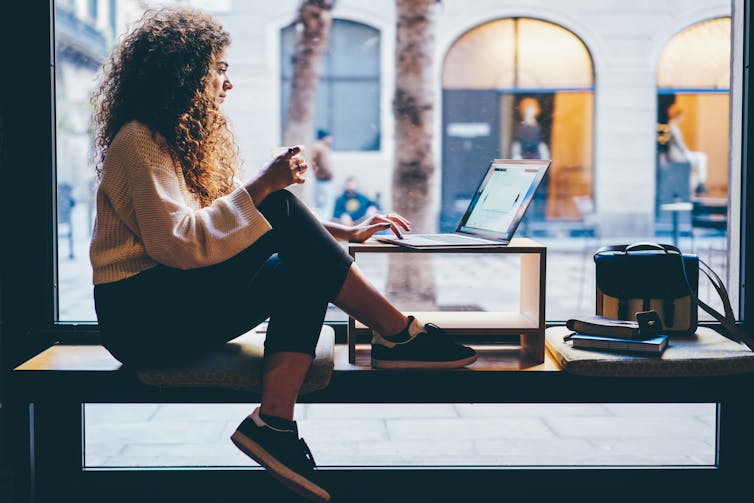 Woman sitting in a window using a laptop.