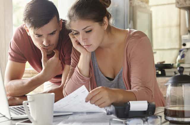 A young couple looks at financial papers in distress