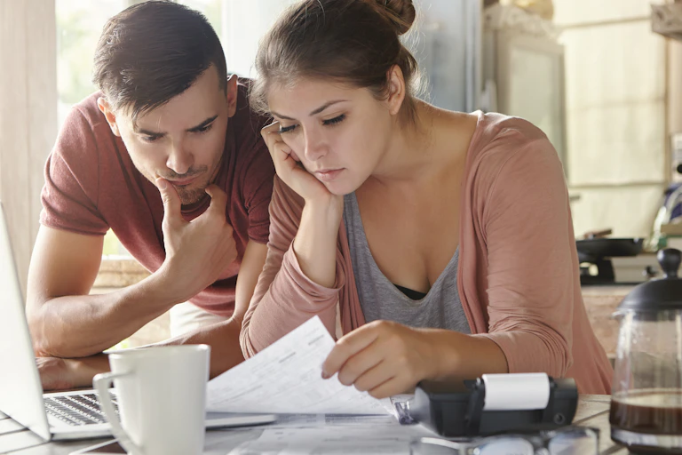 A young couple looks at financial papers in distress