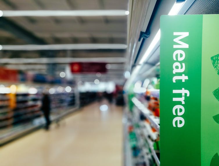 Aisles in a supermarket with one section labelled as 'meat free.'
