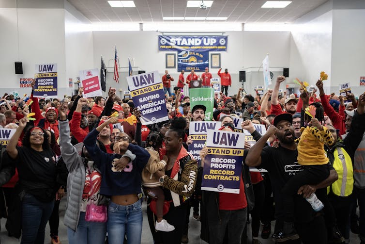 UAW members, some holding their children aloft, attend a rally.
