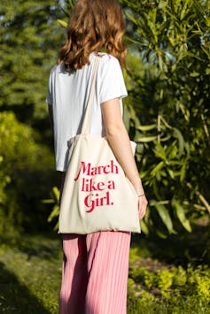 Woman carrying a tote bag that says march like a girl.