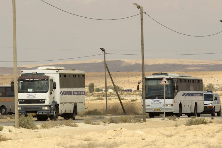 Two buses driving through an arid landscape.