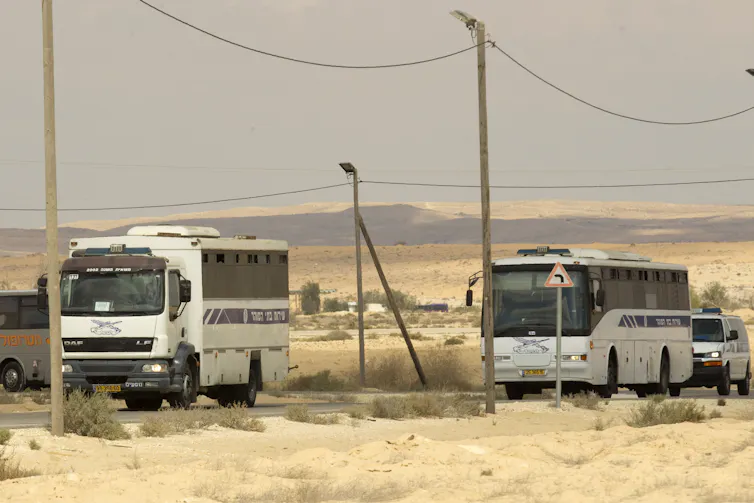 Two buses driving through an arid landscape.