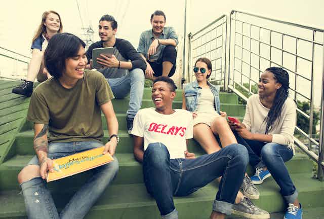 A diverse group of young people sitting on outdoor stairs, smiling and chatting
