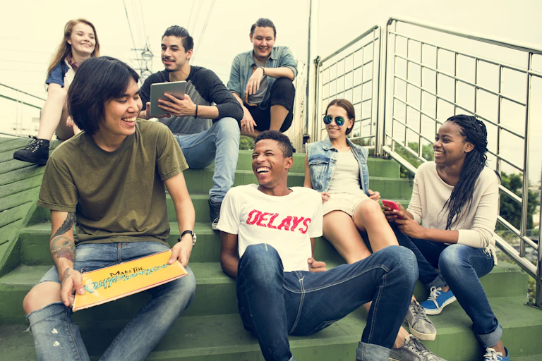 A diverse group of young people sitting on outdoor stairs, smiling and chatting