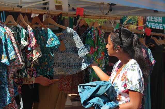 Young woman looks at clothes on a rack at a market stall