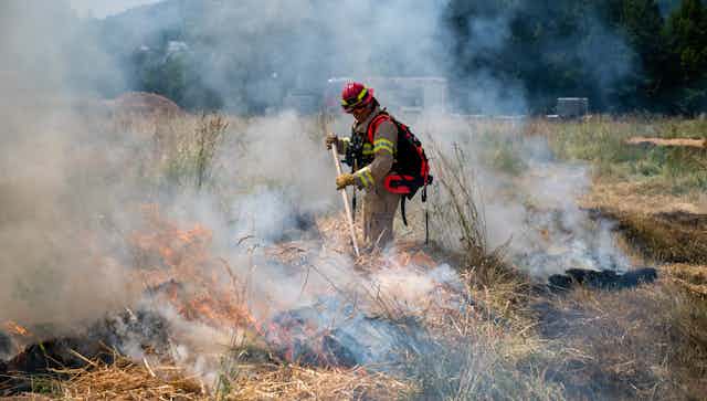 A firefighter controlling a fire on farmland.