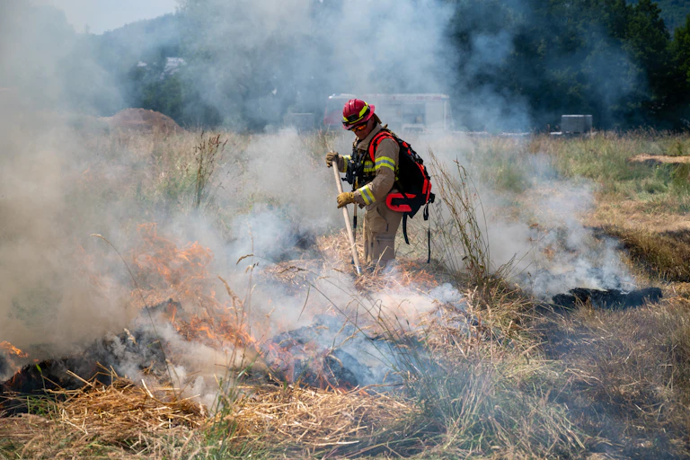 A firefighter controlling a fire on farmland.
