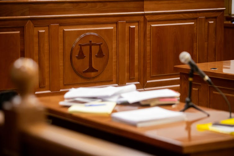 A courtroom with a view of the scales of justice on a wooden panel.