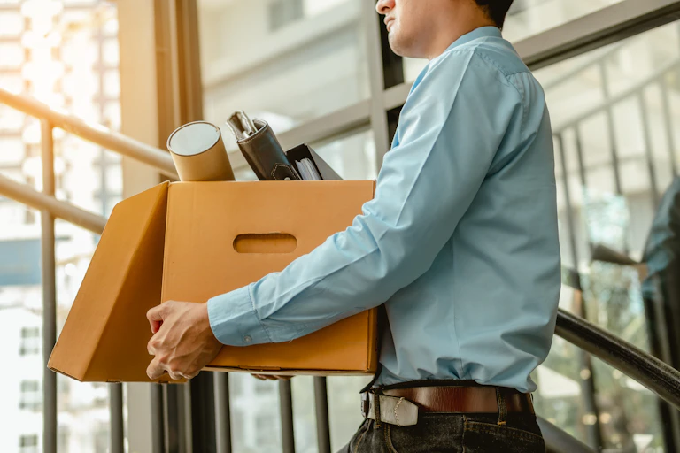 A businessman carrying a box filled with his possessions after resigning.
