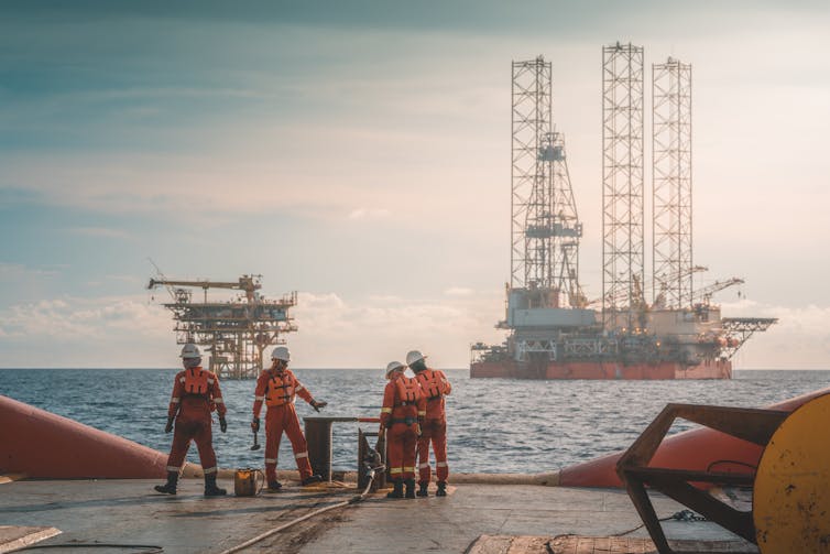 Four workers standing on an offshore oil rig.