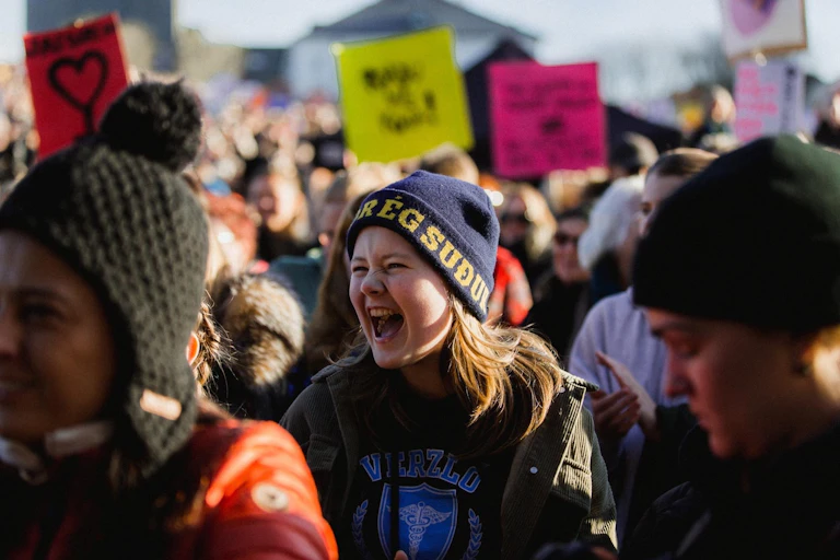 Woman shouting in a crowd of people with signs.