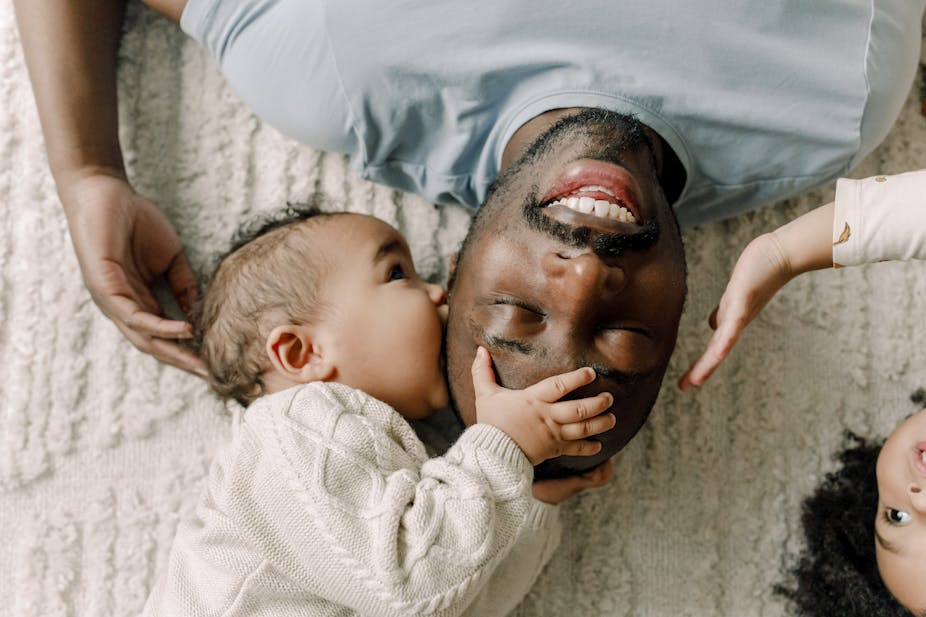 Un homme, un bébé et un jeune enfant allongés et se touchant affectueusement