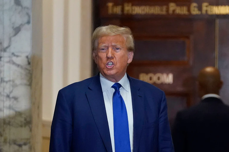 Donald Trump speaks in a hallway outside a courtroom.