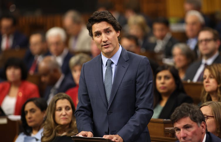 Justin Trudeau wearing a dark suit standing and speaking.