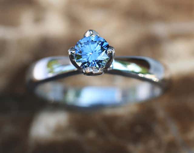 A blue gem on a silver ring, photographed close-up.