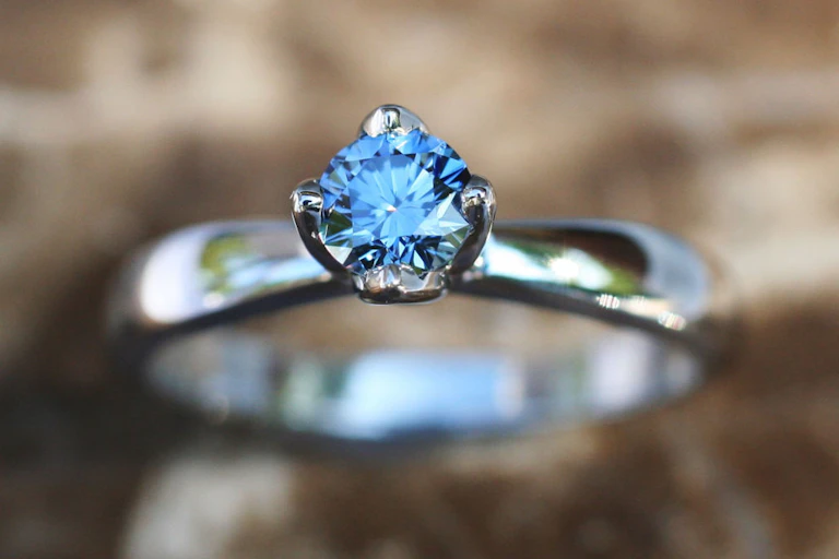 A blue gem on a silver ring, photographed close-up.
