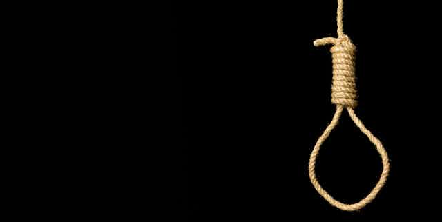 A rope noose hangs against a black background.