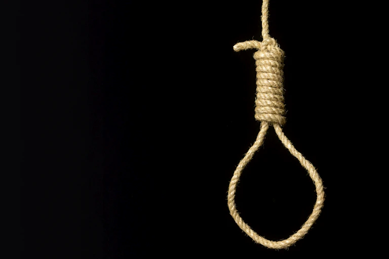 A rope noose hangs against a black background.