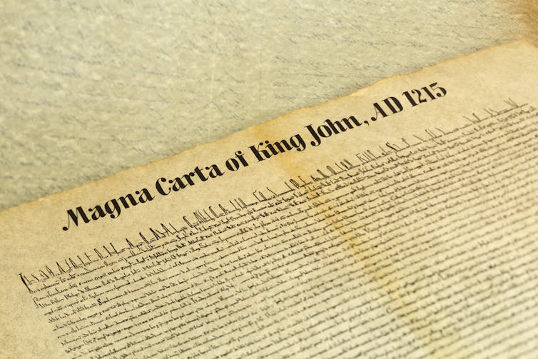 A close up shot of an ancient document, reading 'Magna Carta of King John, AD 1215'