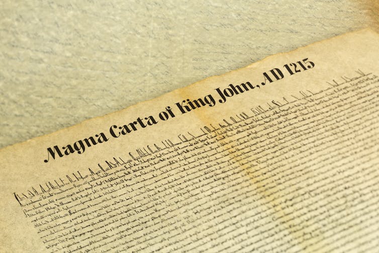 A close up shot of an ancient document, reading 'Magna Carta of King John, AD 1215'