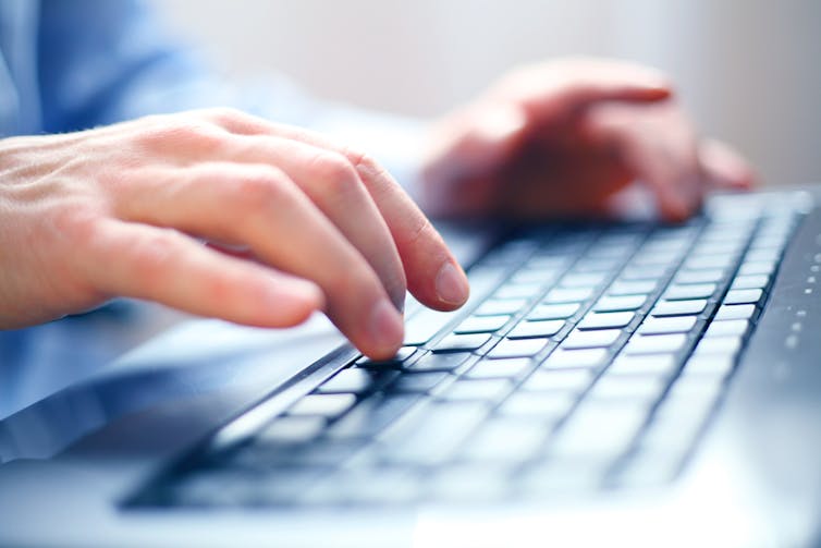 A person types on a computer keyboard