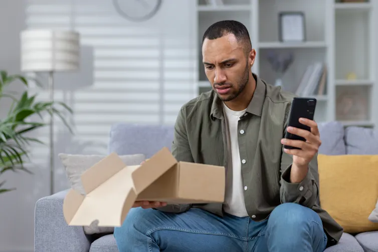 A man looks disappointed when he opens a package.