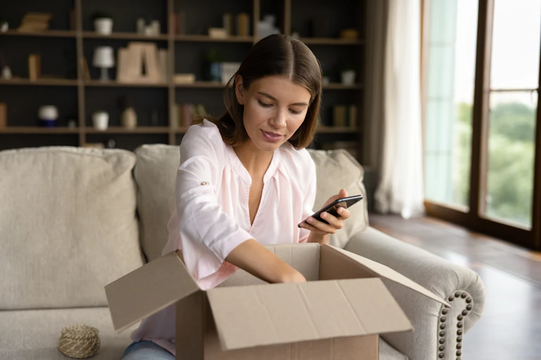 A woman opens a package in her home.