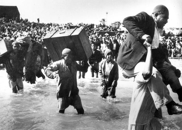 A large number of people, some holding their luggage, as they try to flee.