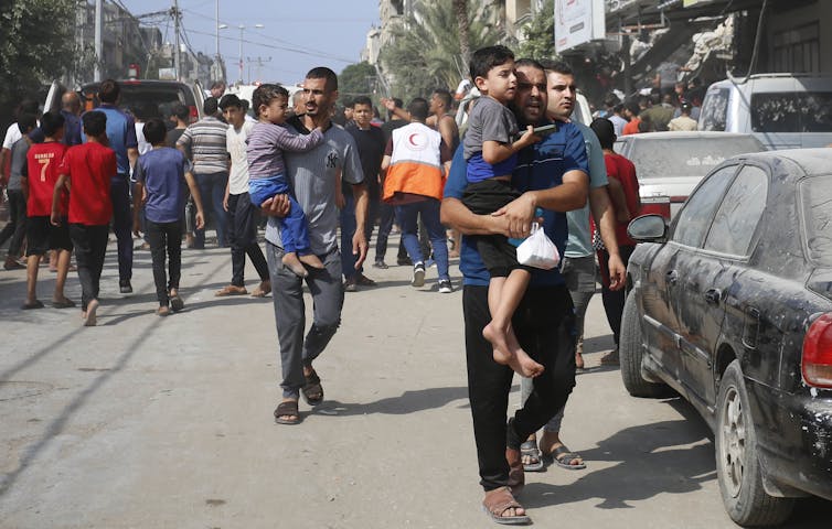 Families, holding children in their arms, leave areas near the fighting in Gaza.