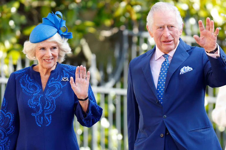 A man and woman dressed in blue holding up a hand in a wave