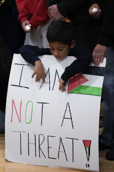 A young boy holds a placard that reads: I am not a terrorist