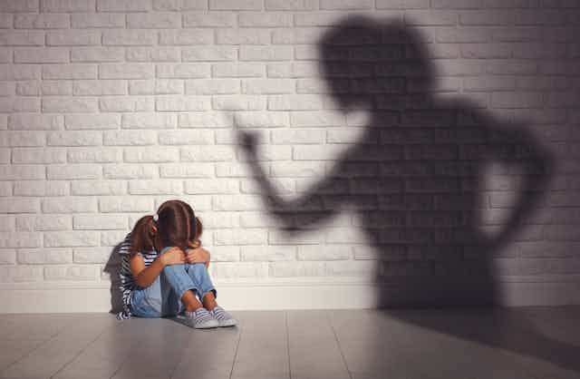 A person in shadow shouts at a scared child.
