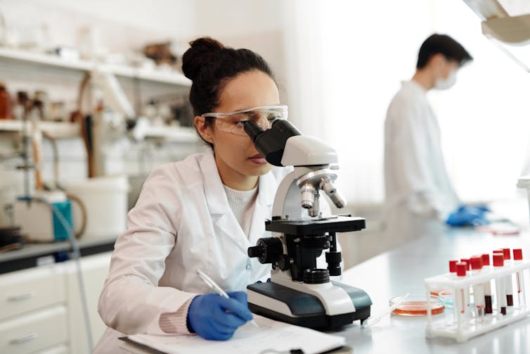 Female scientist looks in microscope