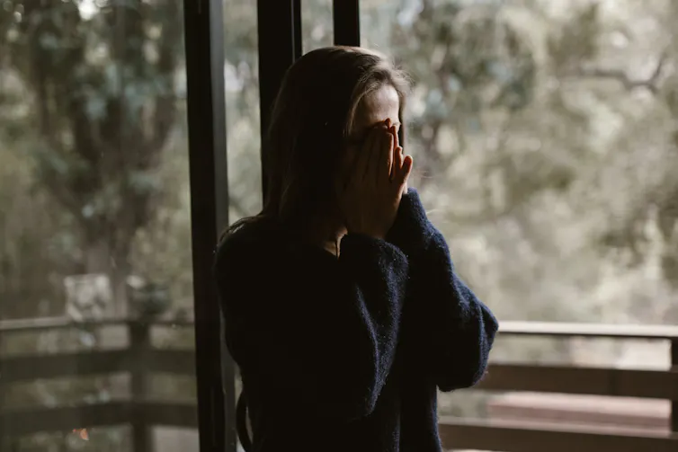 A woman at a window crying.