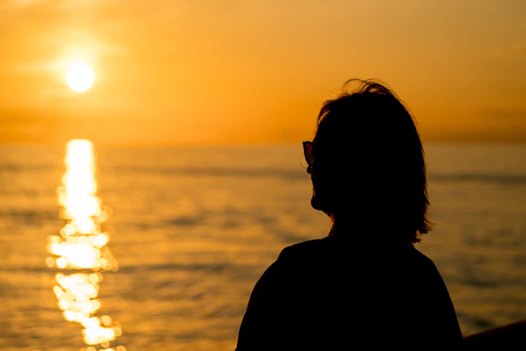Woman looks at sun above the horizon