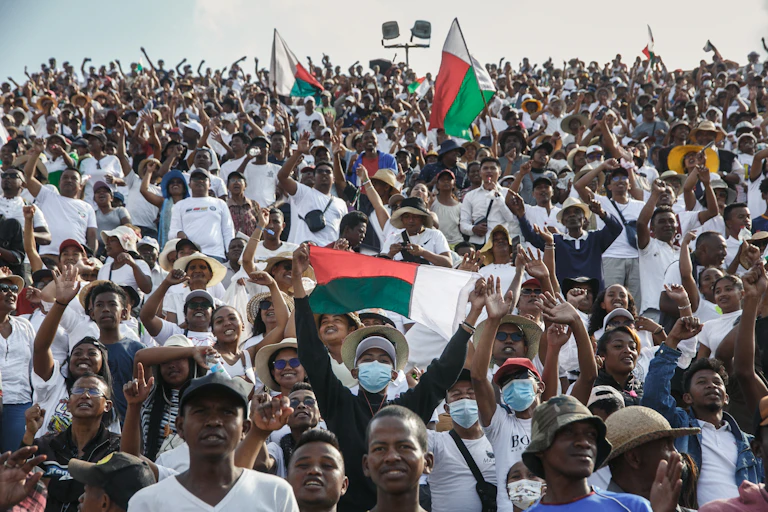 A crowd of people, some holding flags